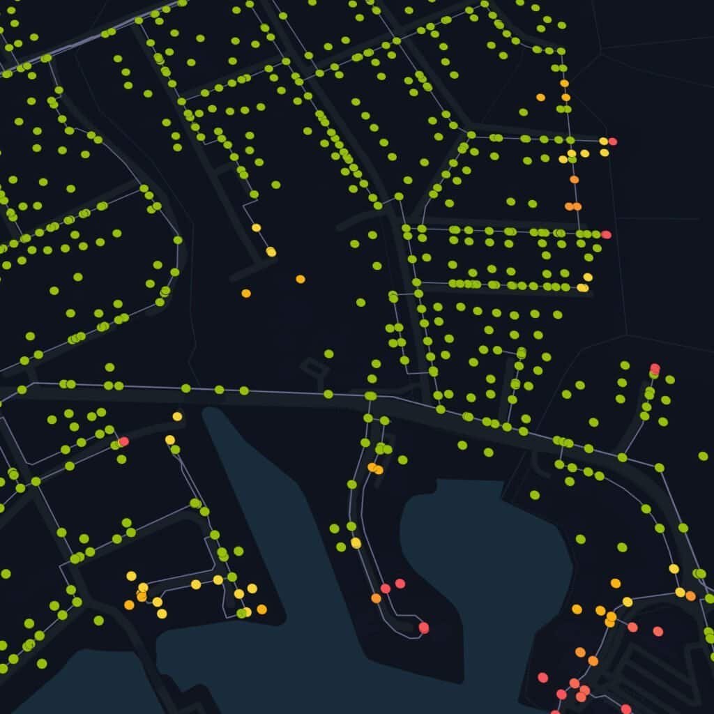A dark map shows streets near a body of water, with dots in green, yellow, orange, and red marking various locations along the roads and shoreline.